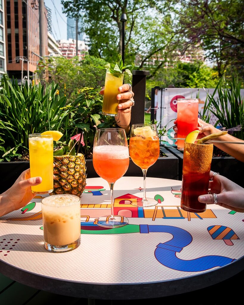 Civil Parks | Shot of several vibrant cocktails with lush greenery in the background | Homes Almanac