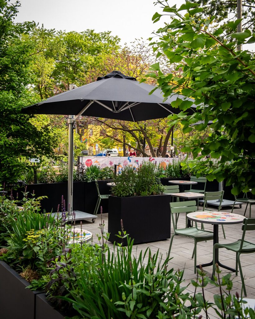 Civil Parks by Civil Works | Lush outdoor patio with a black umbrella and seating | Homes Almanac