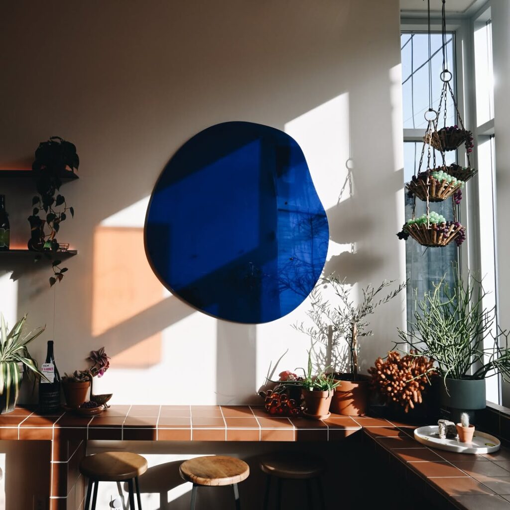 Ossington Wine Crawl | Interior shot with light shining through the window against the wall with a blue decor piece hanging over a tile bar | Homes Almanac