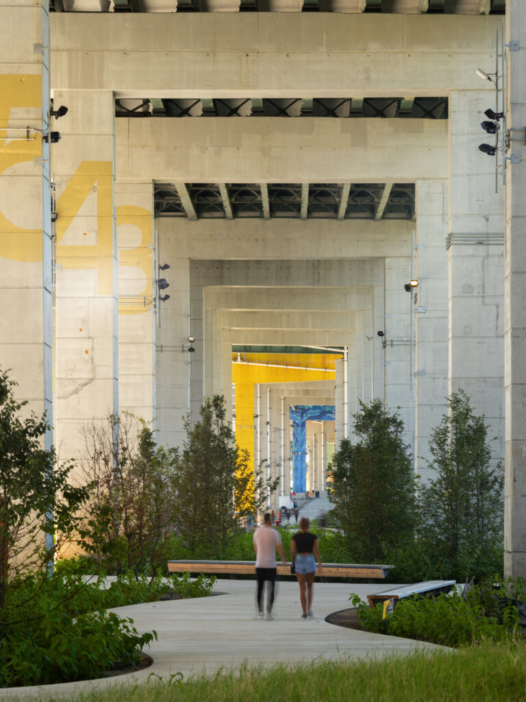 Beneath the Gardiner at The Bentway | Soft daylight coming in from the left with concret columns, greenery and people walking | Homes Almanac