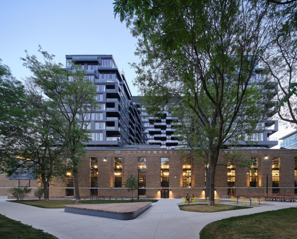 King and Portland | Evening exterior of Waterworks Food Hall dimly lit with trees overhanging | Homes Almanac