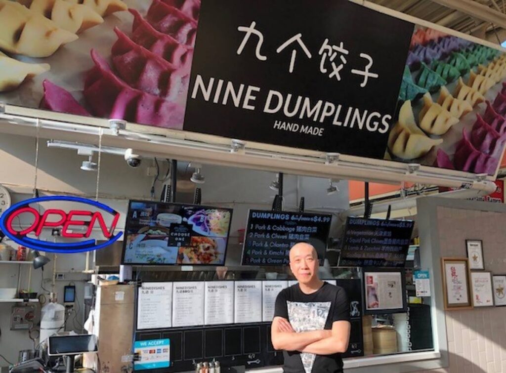 Nine Dumplings Vancouver | Owner of Nine Dumplings standing outside of food stall | Homes Almanac