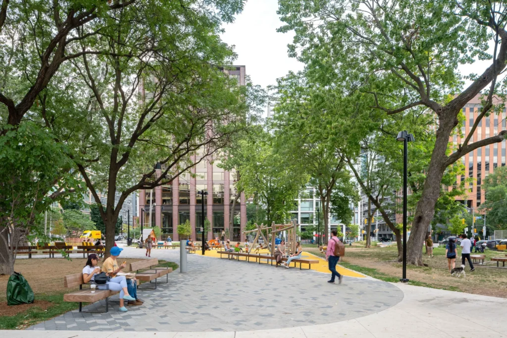 Historic Downtown Toronto Park | People sitting on park benches and walking through the treelined pathway through the park | Homes Almanac
