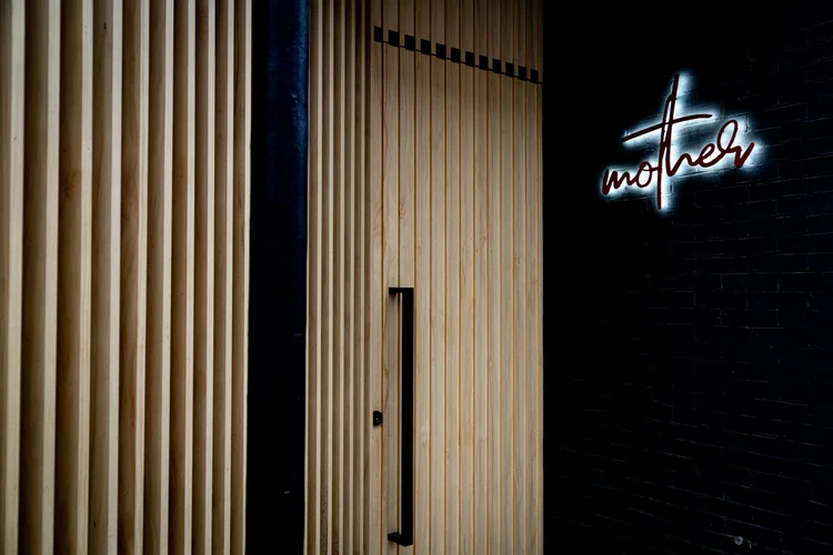 mother cocktails toronto | entrance of Mother with oak wood slats and a minimal sign | Homes Almanac