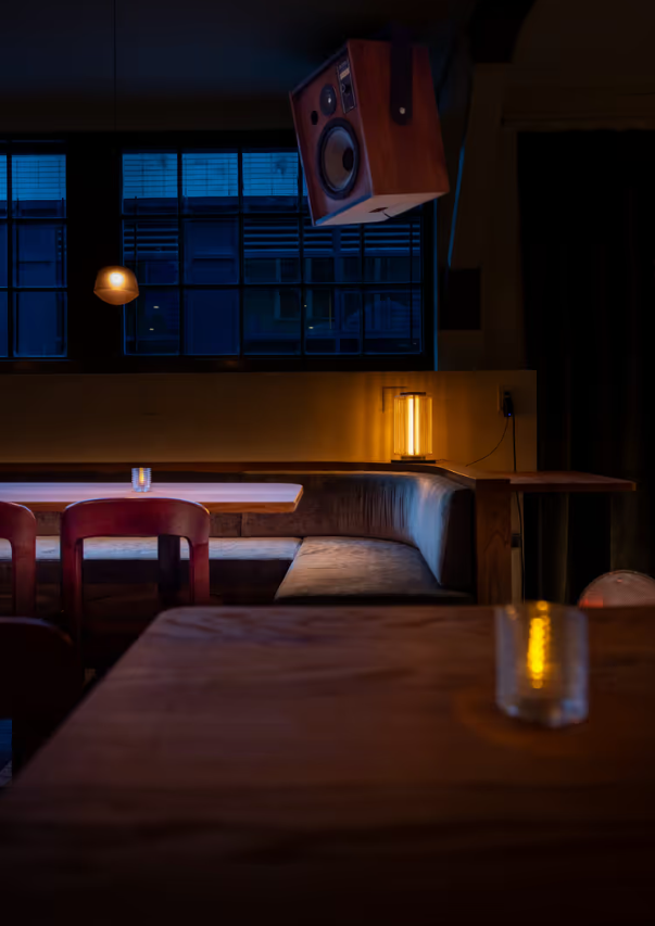 A table and booth with a speaker in view at Osteria Otto restaurant  | Osteria Otto Mount Pleasant | Homes Almanac