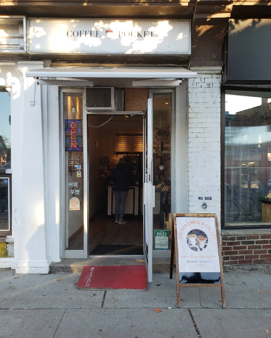 The Coffee Pocket | A small entrance with white brick and a square red carpet at the foot of the open door | Homes Almanac
