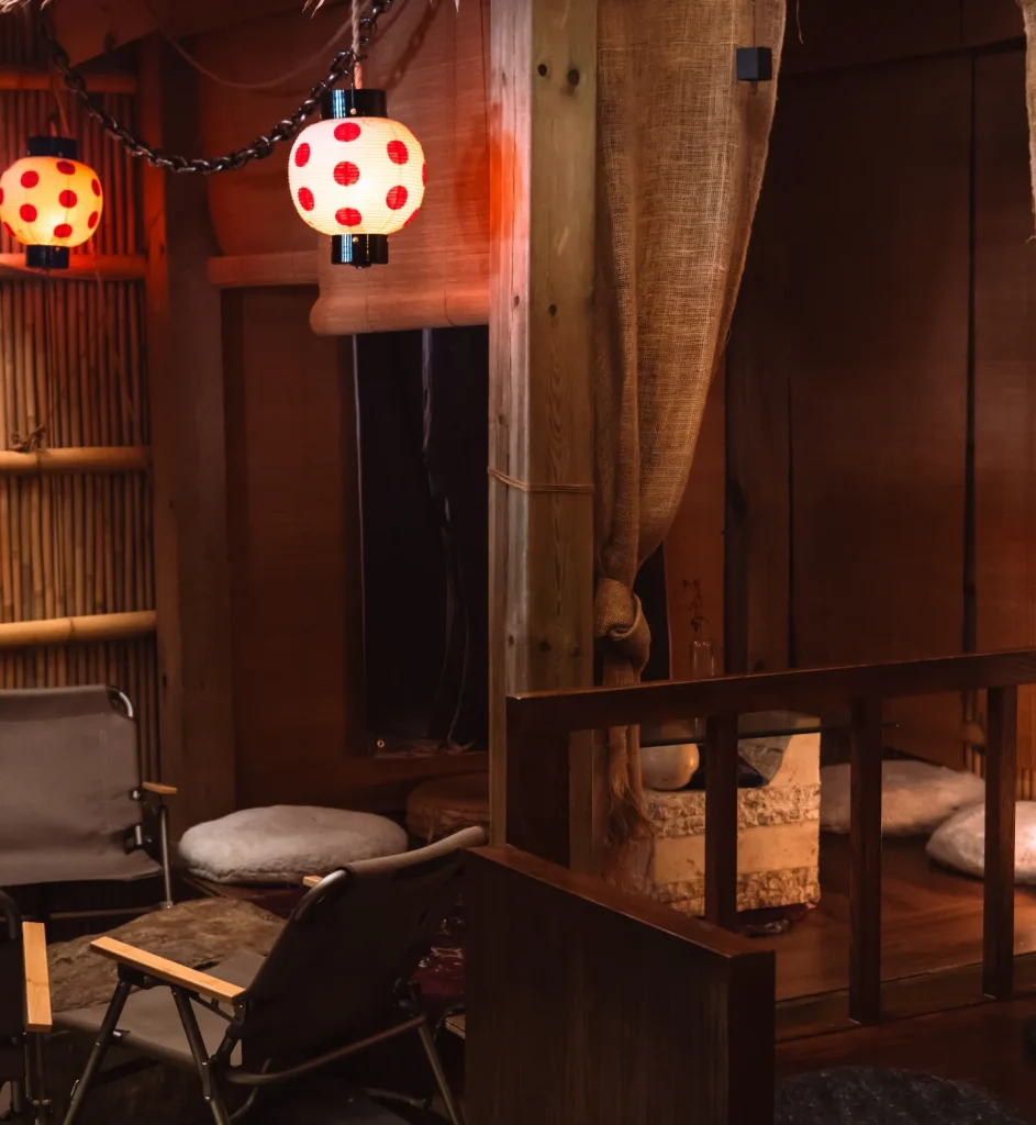 Geary Ave | A cozy dimly lit room with low set seating, bamboo walls and red spotted lanterns hanging from the ceiling | Homes Almanac