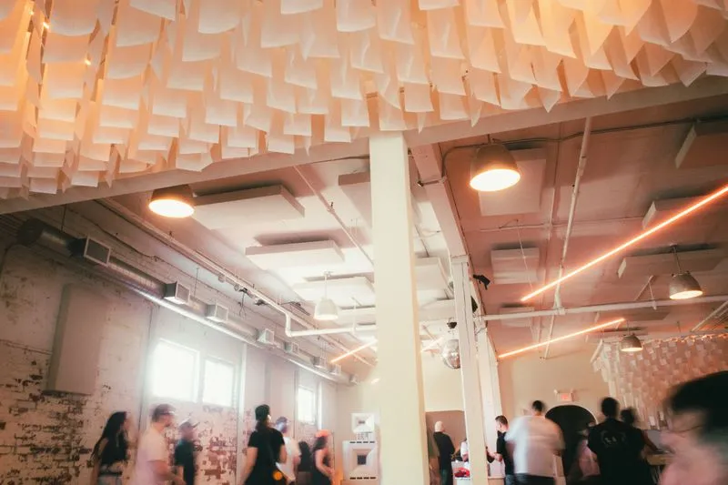 Geary Ave | Bright open warehouse space with white walls and people socializing | Homes Almanac