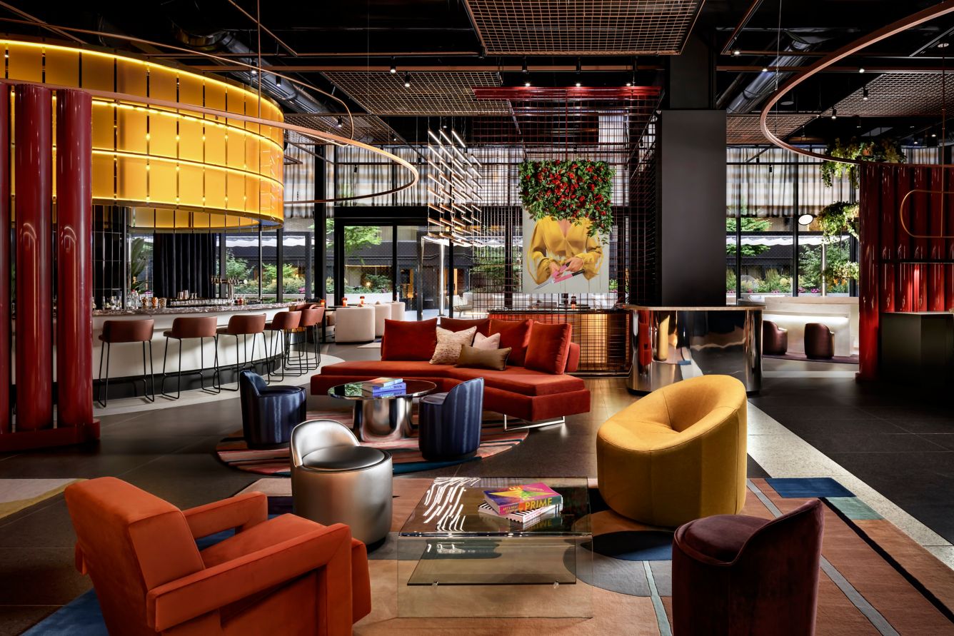W Toronto | Room with floor to ceiling windows and rich red orange and yellow fabric seating | Homes Almanac