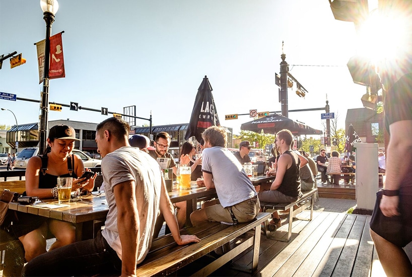 History of Liberty Village | People sitting outside on picnic benches on a patio in a sunny summer day | Homes Almanac