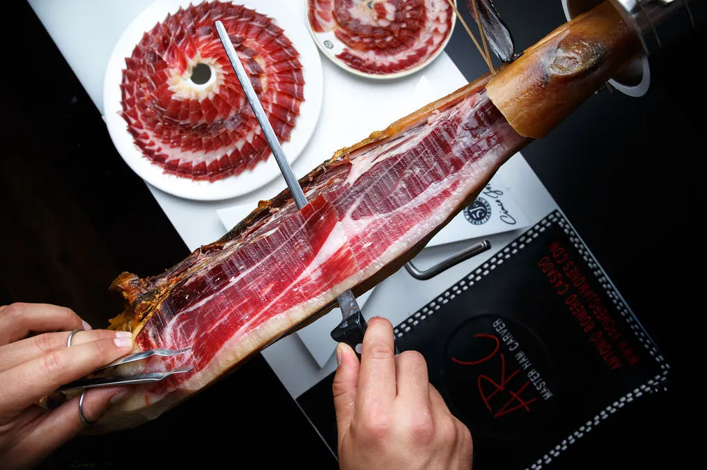 Jamoneria by Arc | Overhead shot of someone slicing into a jamon leg | Homes Almanac