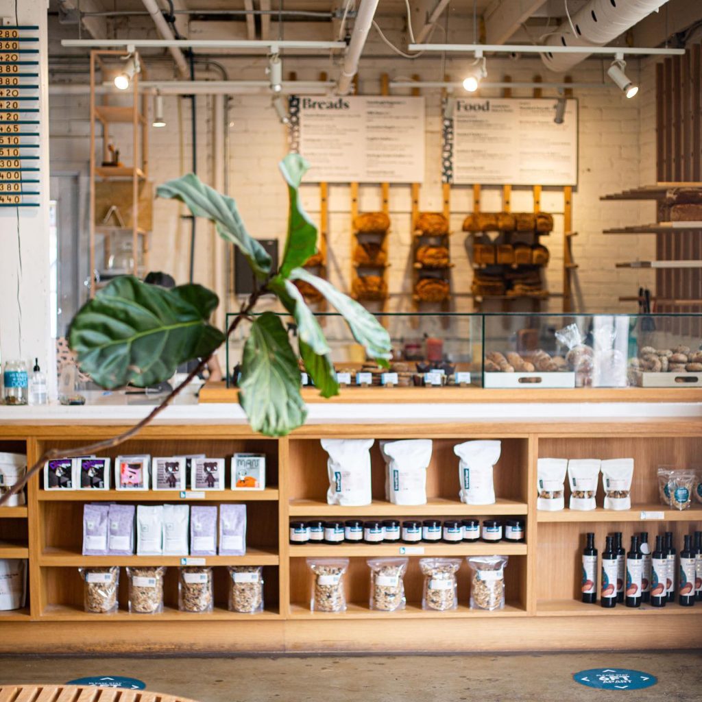 Brodflour | A bright bakery counter with light oak shelving and shelves lined with baked goods and coffee bags | Homes Almanac