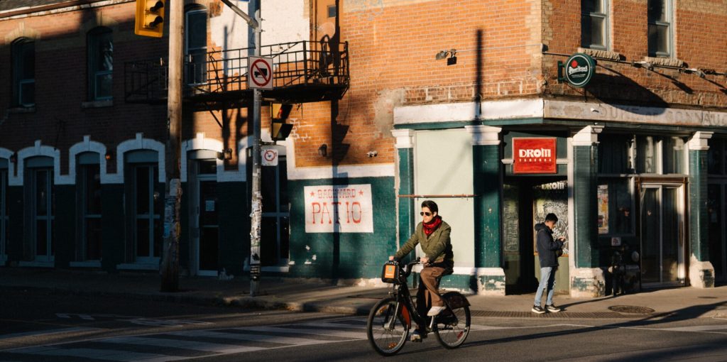 48 Hours in Queen Street West | Sunrise against a brick building with a biker biking by | Homes Almanac