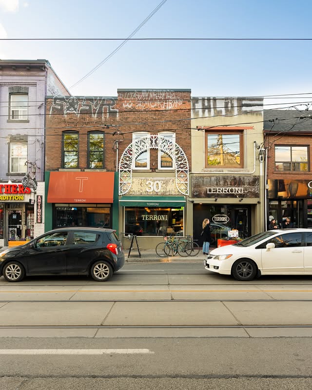 Terroni | Storefront with an arched metal sign and a green awning | Homes Almanac