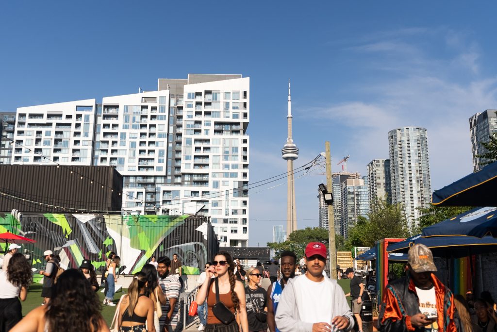 king west itinerary | view of the CN tower from STACKT market on a sunny day with people walking around | Homes Almanac