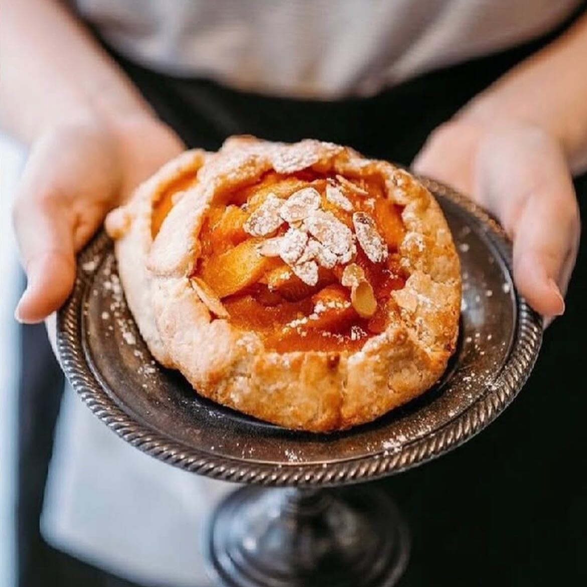 Gluten Free Epicurean | Hands holding a plate with a peach cobbler | Homes Almanac